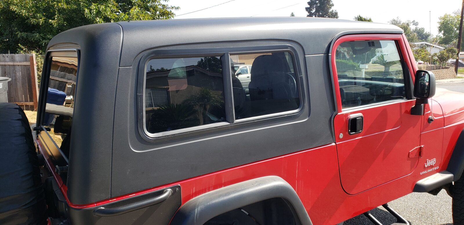 Red Jeep Wrangler LJ Unlimited with black hard top and sliding side window